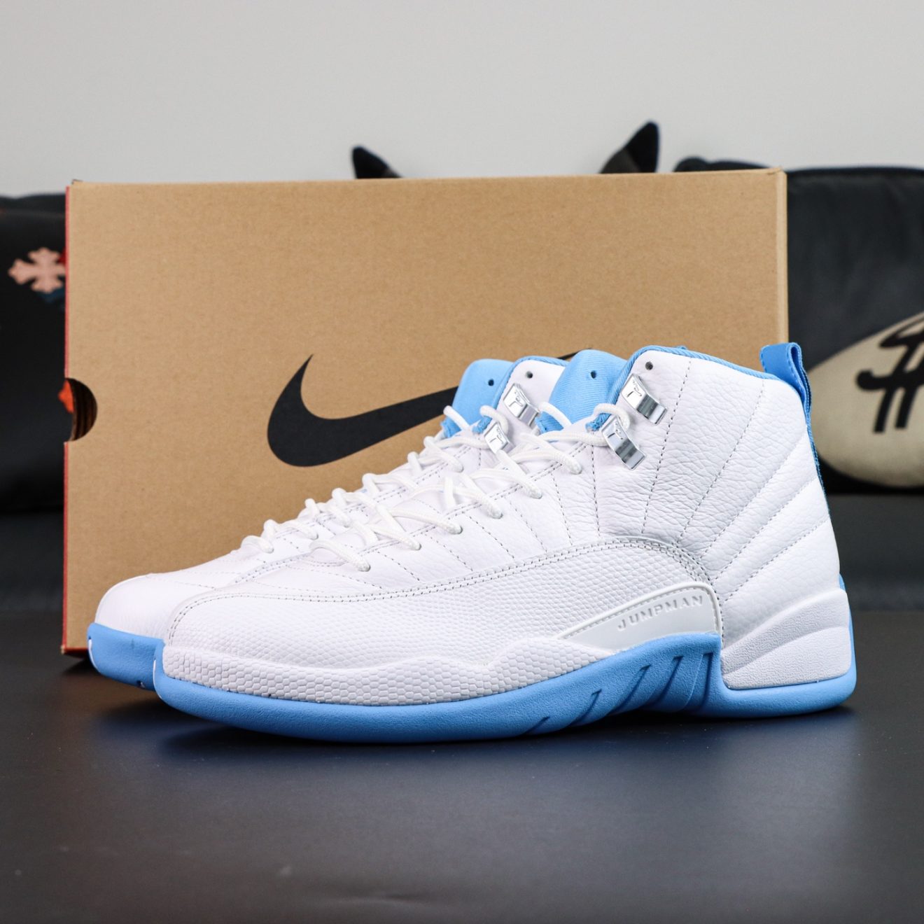 Jordan 12 Melo 2025 reps with white leather and University Blue details beside box