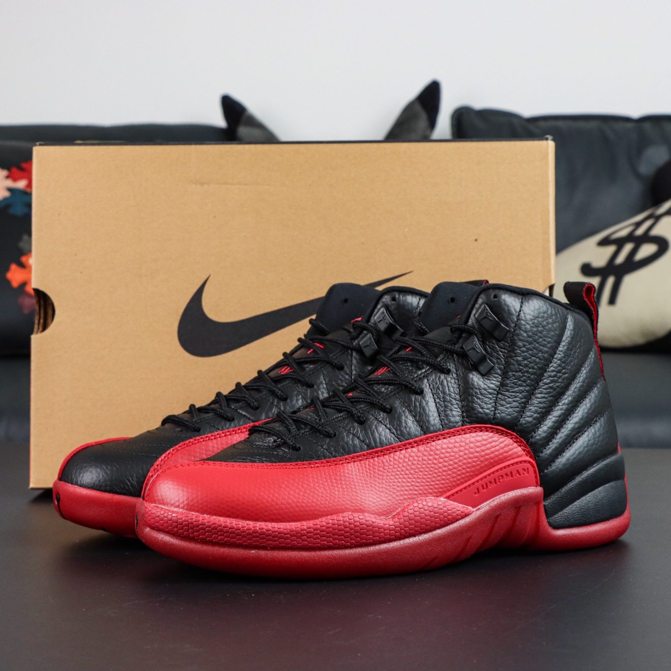 Jordan 12 Flu Game 2025 reps with black and red upper beside retail-style box